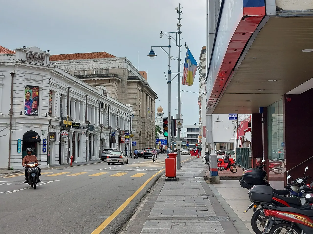 Beach Street in George Town, Penang: white colonial shopfronts, a clock tower and motorcycles parked under an arcade